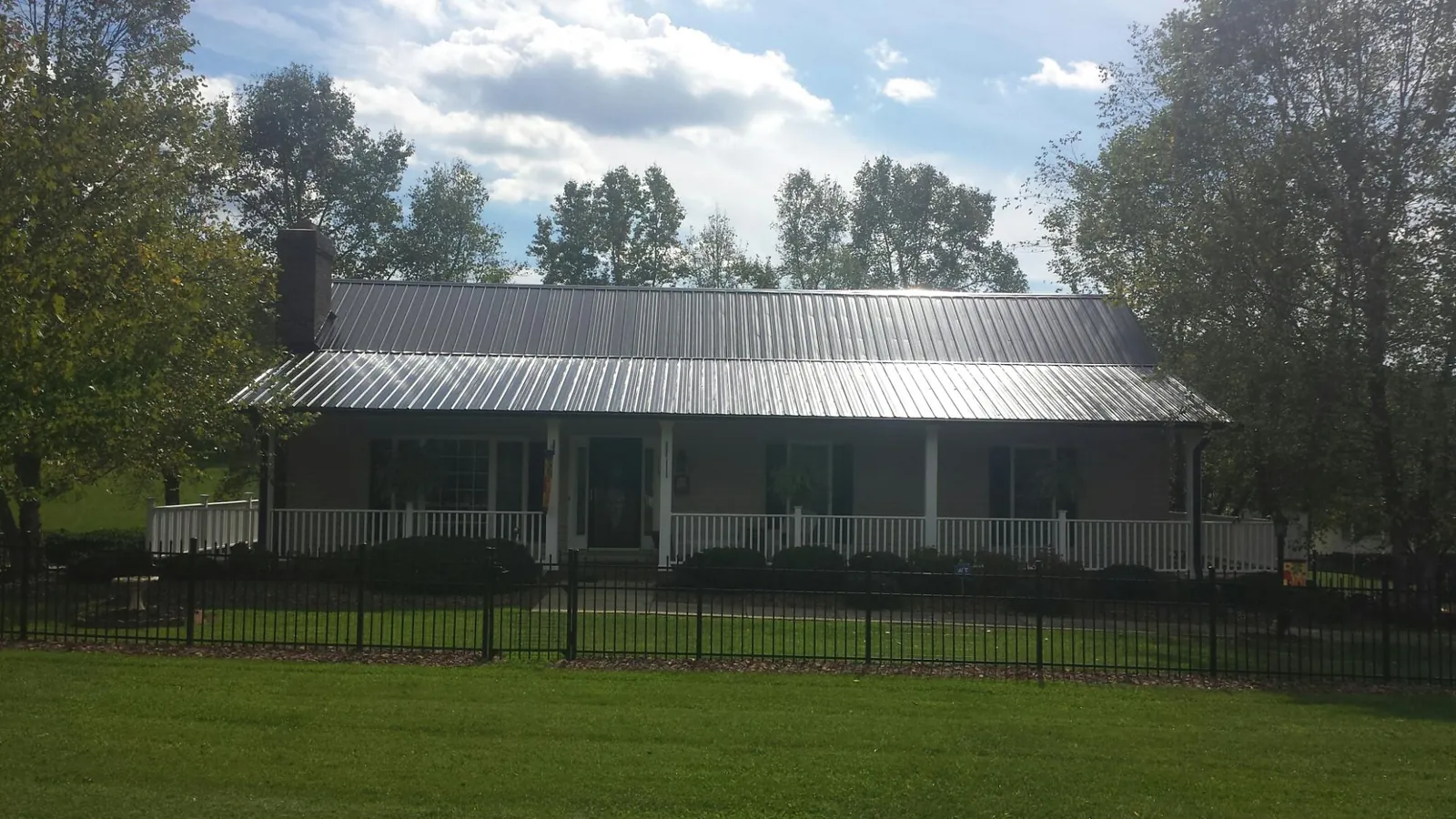 Gray metal roof on a brick ranch with a full width front porch — Gutter Guard Installation work by our crew in Roanoke Rapids