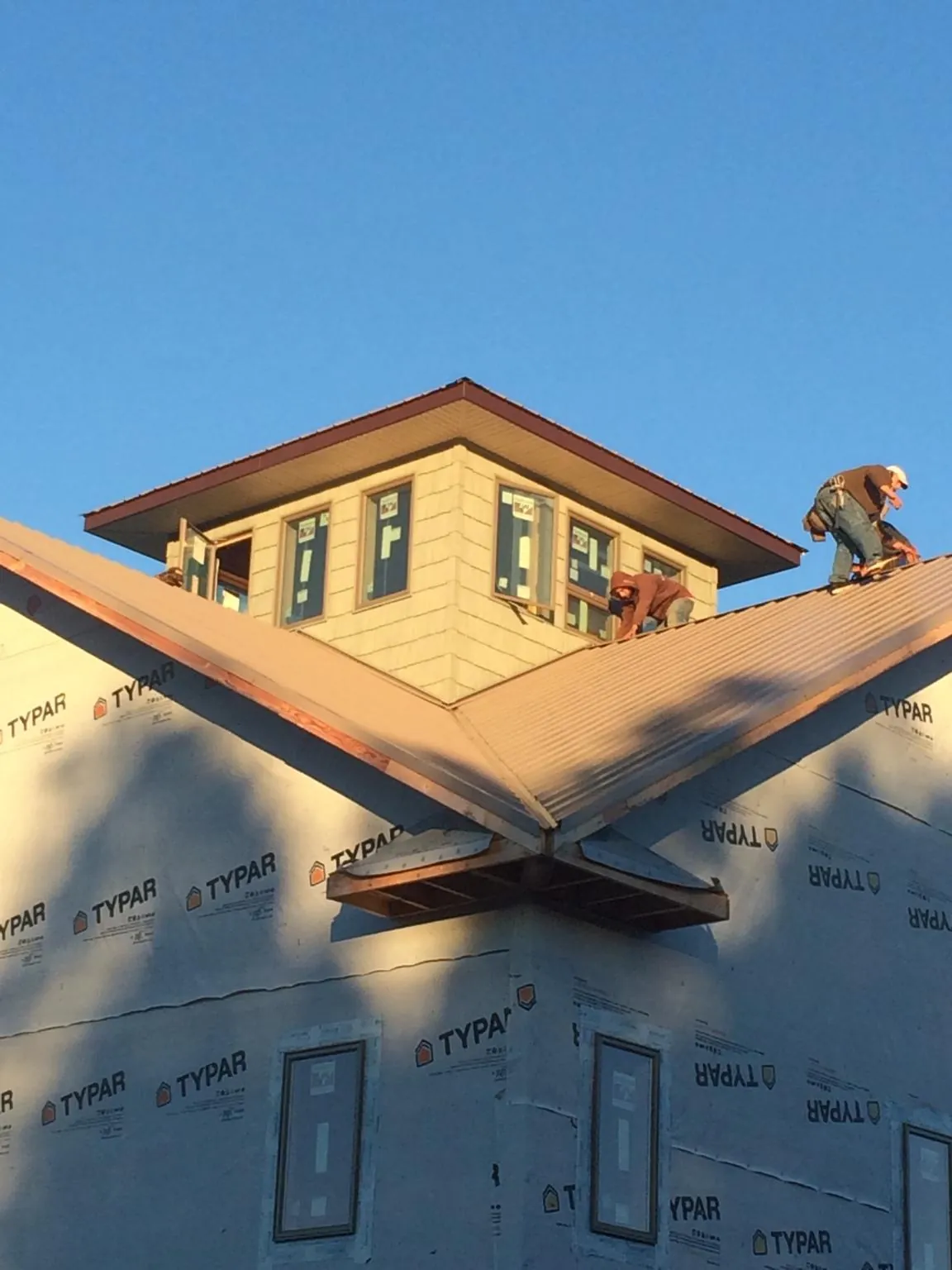 Roofers working around a rooftop cupola on a new metal roof at sunset — Roof Waterproofing in Roanoke Rapids by Roofing Brothers